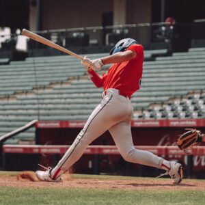 player in red jersey shirt and white shorts holding baseball bat