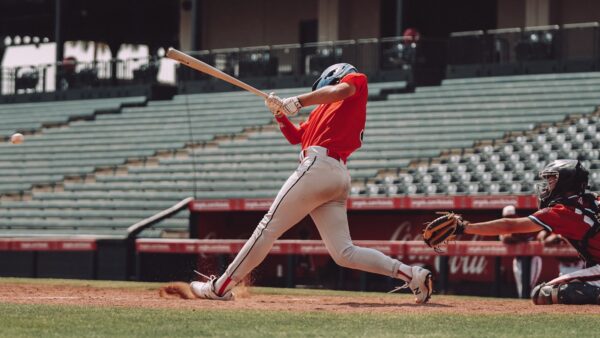player in red jersey shirt and white shorts holding baseball bat